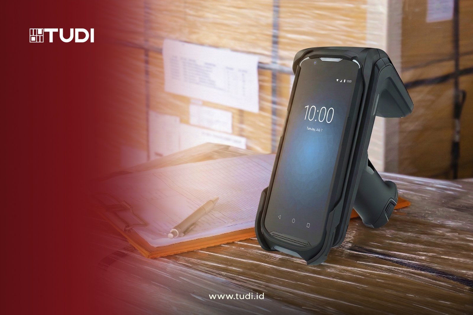 Handheld device with screen at 10:00, set on plastic-wrapped pallets, next to papers and pen. Branding "TUDI" and website "www.tudi.id".