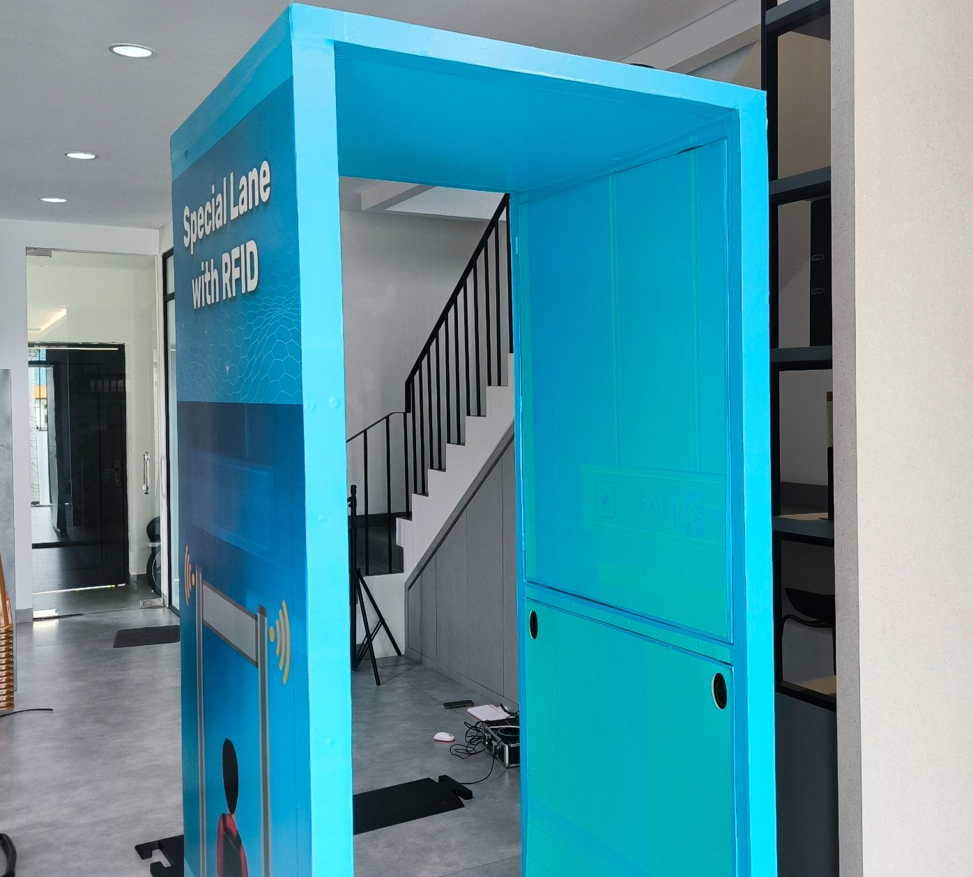 Blue RFID lane device in modern indoor setting. Sign on device reads "Special Lane with RFID." Staircase and equipment visible behind.