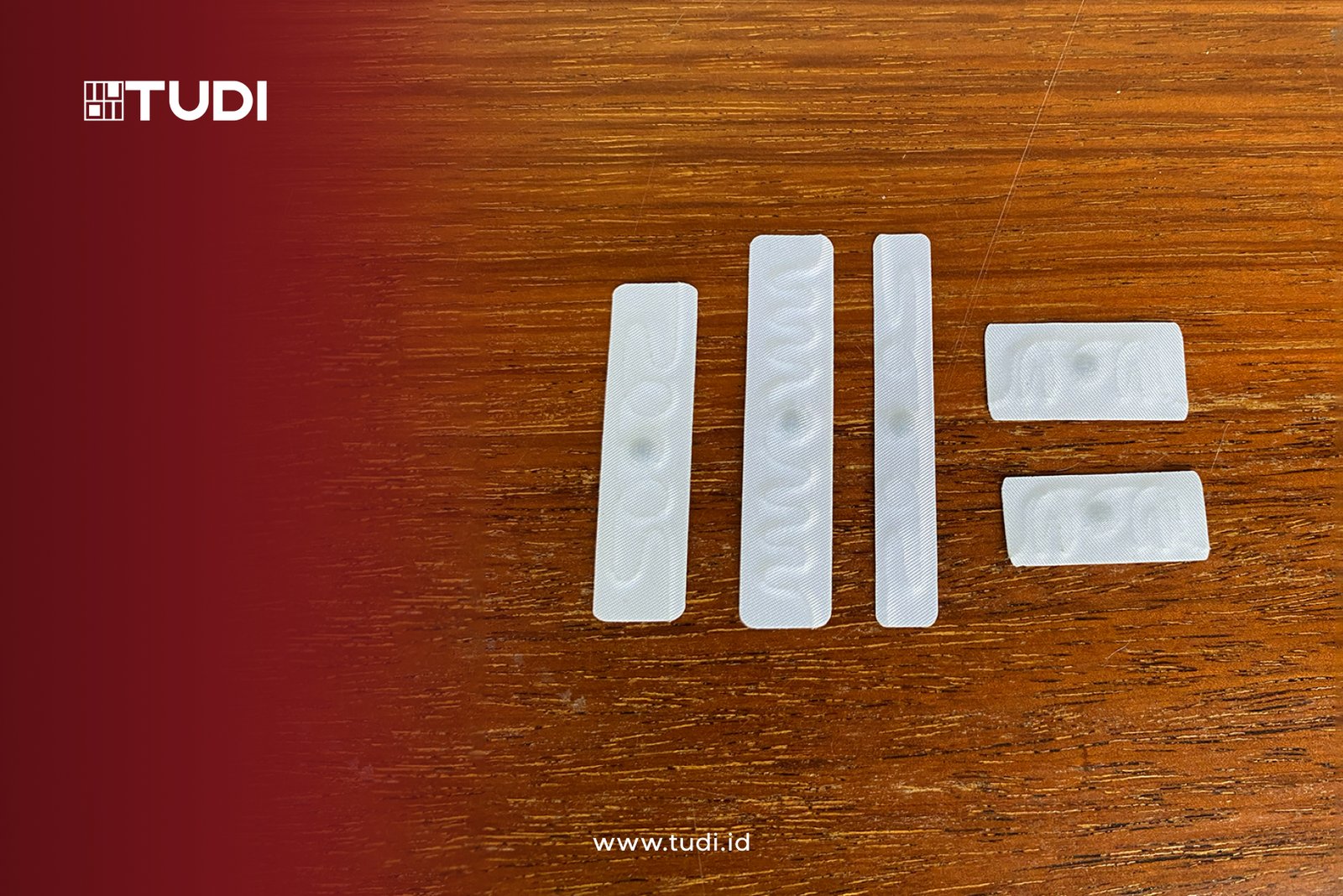RFID linen on a wooden surface with embossed patterns. Red gradient on left with "TUDI" logo. Text below: "www.tudi.id".
