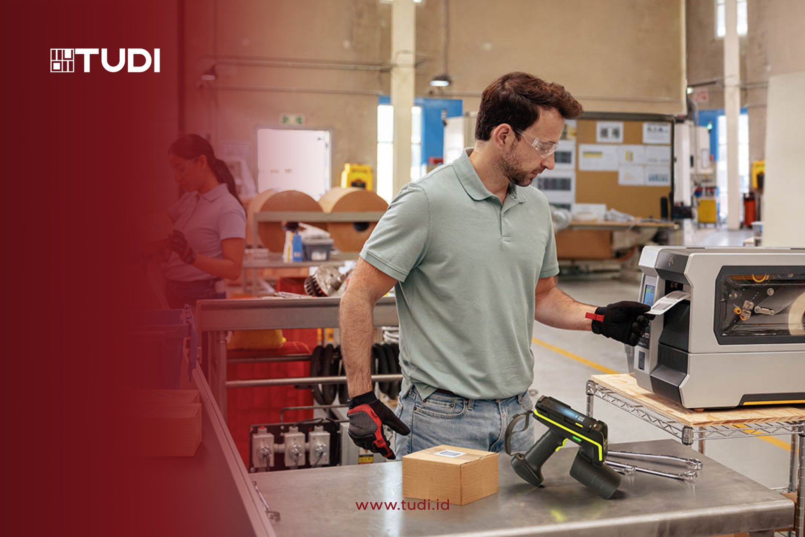 Man in safety goggles operates a RFID label printer in an industrial setting. A box and scanner are on the table. Background shows busy workshop.