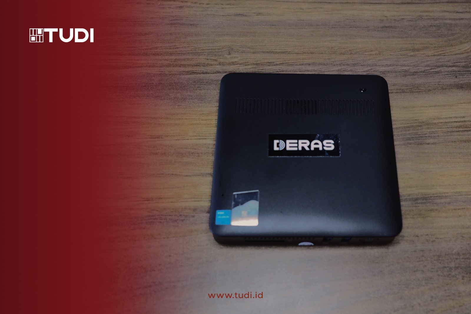 Black device labeled "DERAS" on wooden table. Logo "TUDI" and "www.tudi.id" text on red gradient background.